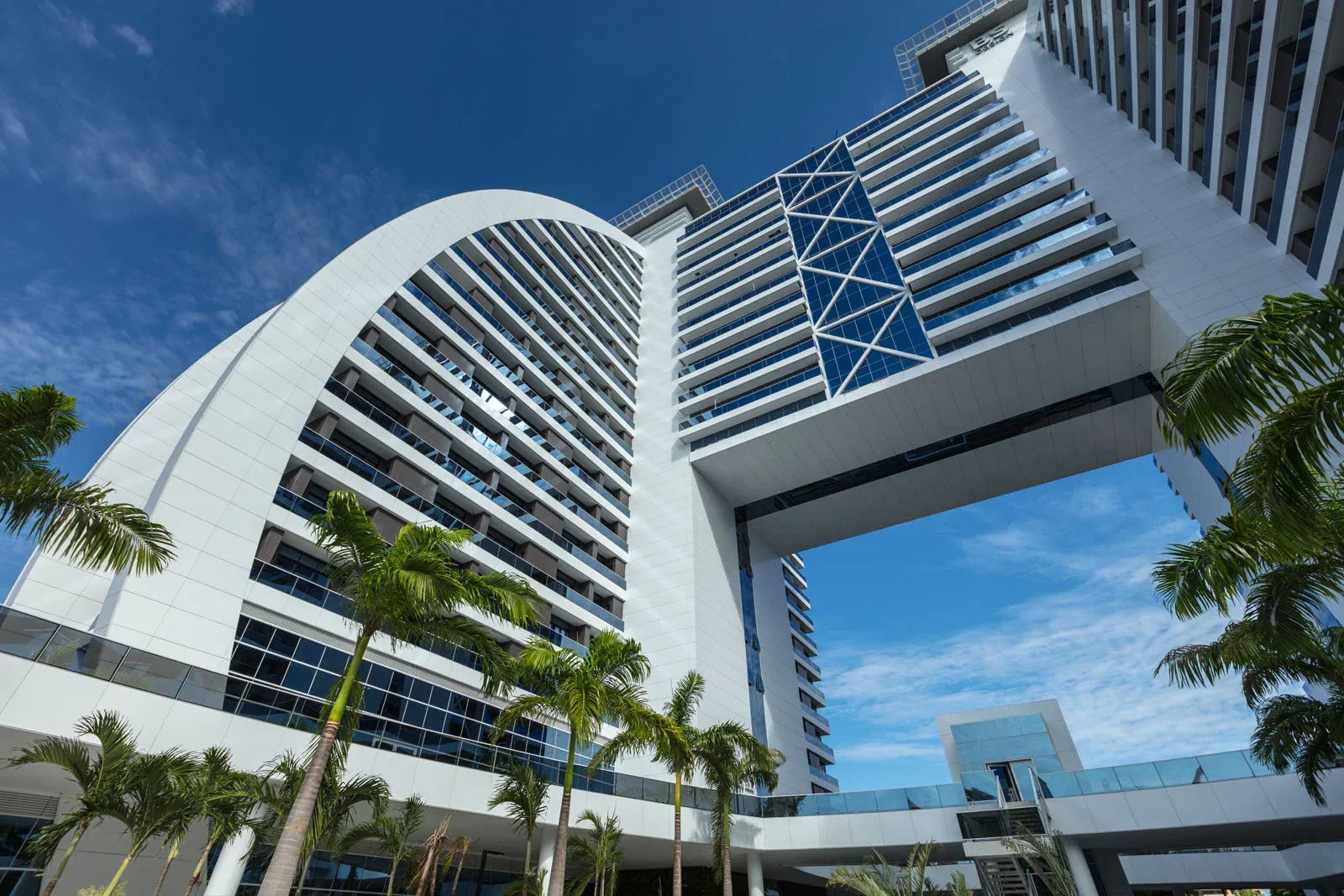 Edifício BS Design visto de baixo, com arco e palmeiras