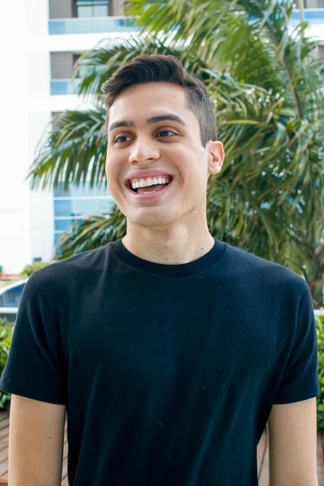 paciente_jovem-homem-moreno-camisa-preta-sorrindo-palmeira-exterior_14-zpc